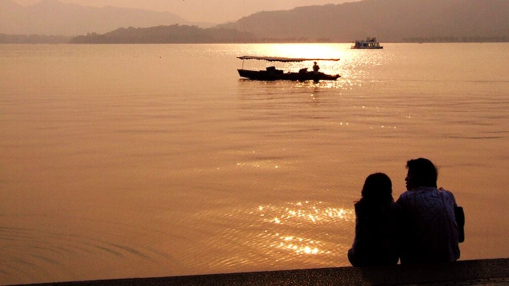 Couple relaxing with the sunset view along the waters in Hangzhou 