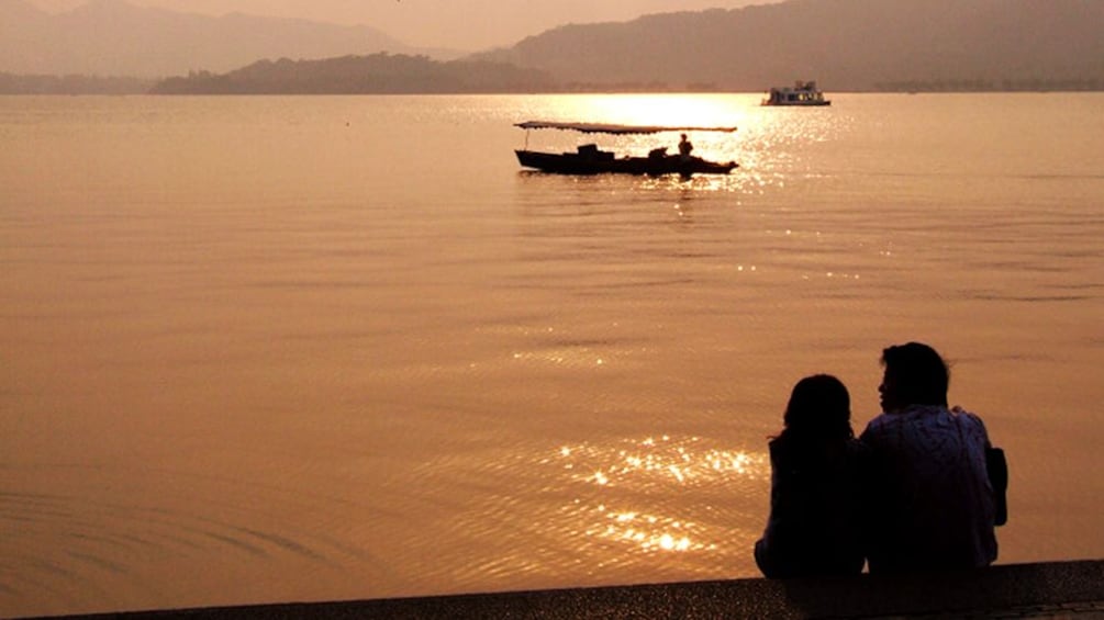Couple relaxing with the sunset view along the waters in Hangzhou