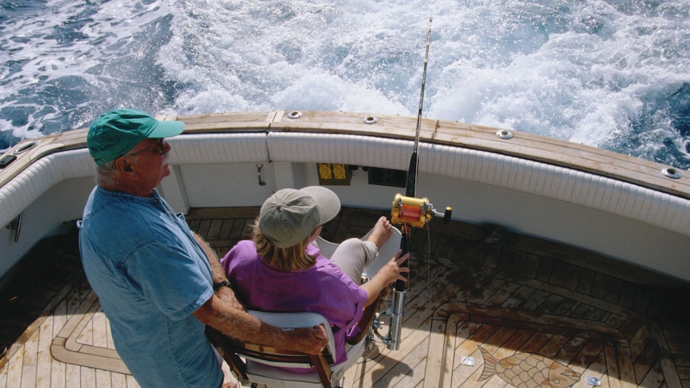 Mature couple sitting on the deck of a boat with a deep sea fishing pole in St Kitts