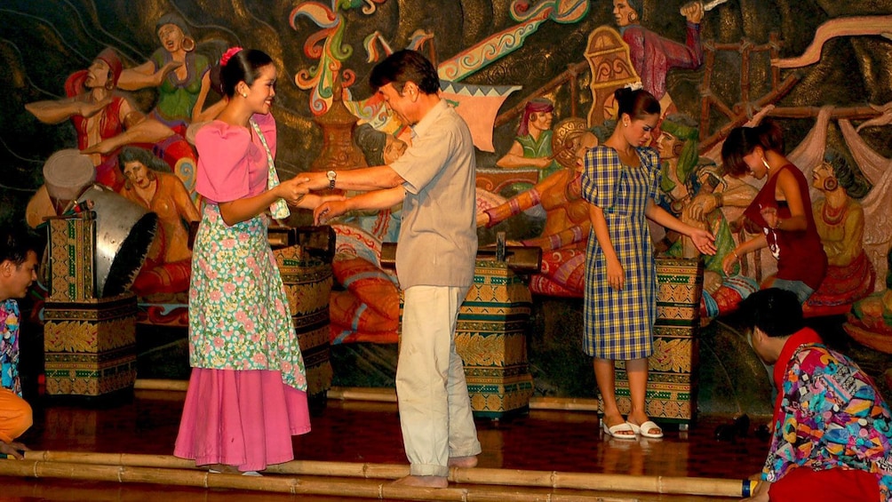 Audience members are invited onstage to dance with the performers during a show in Manila
