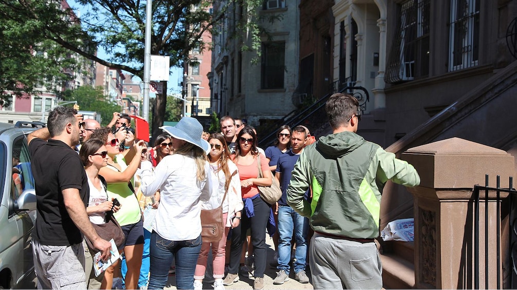 Group with guide outside a brownstone building in Harlem, New York
