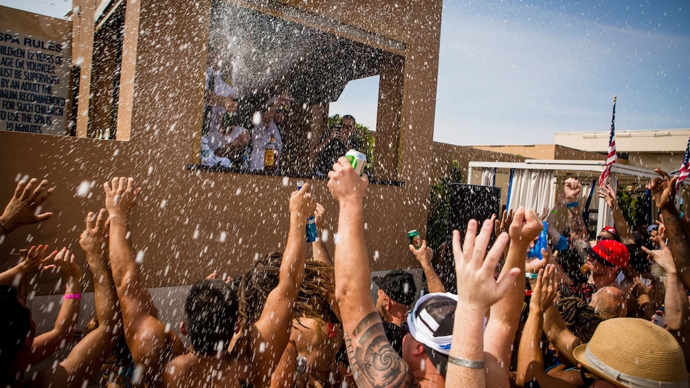 Guests at the Las Vegas pool party raising their hands and drinks in the air