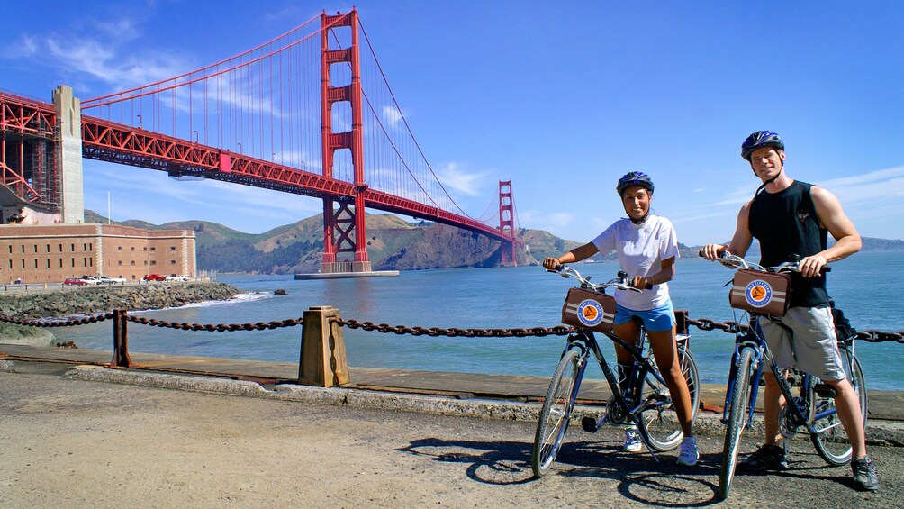 Two people on bikes next to the Golden Gate Bridge