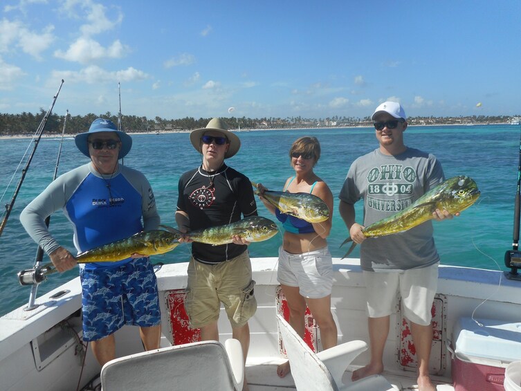 Four tourists hold fish on boat in Punta Cana