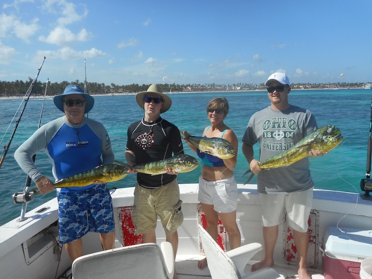 Four tourists hold fish on boat in Punta Cana