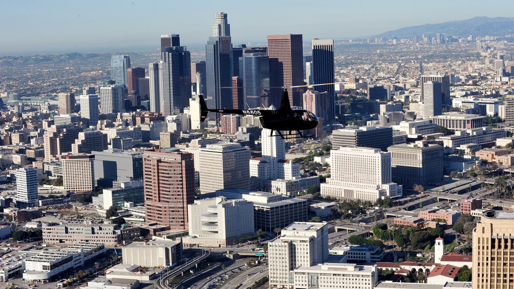 Black helicopter flying above the city of Los Angeles during the daytime 