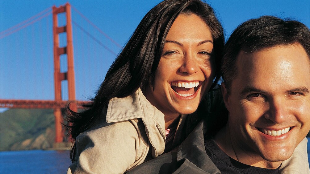 Couple smiling in front of the Golden Gate Bridge in San Francisco 
