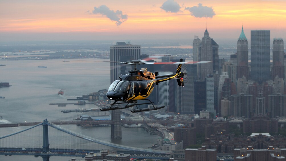 A Helicopter flying above the New York skyline at dusk