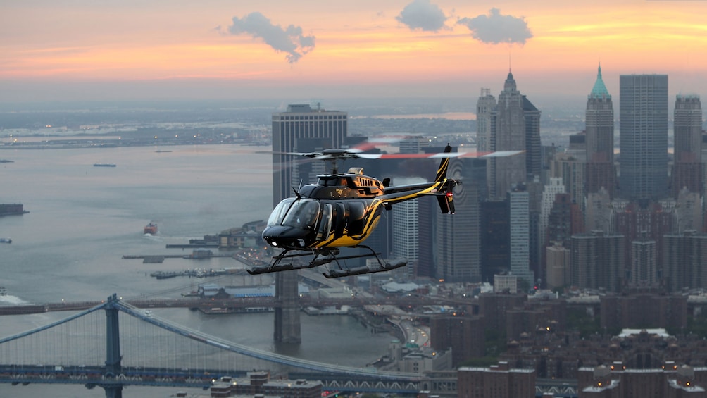 A Helicopter flying above the New York skyline at dusk