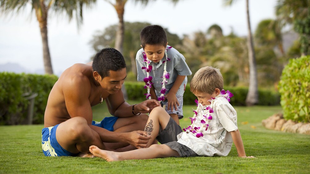 Man painting tribal art on young boy in Oahu