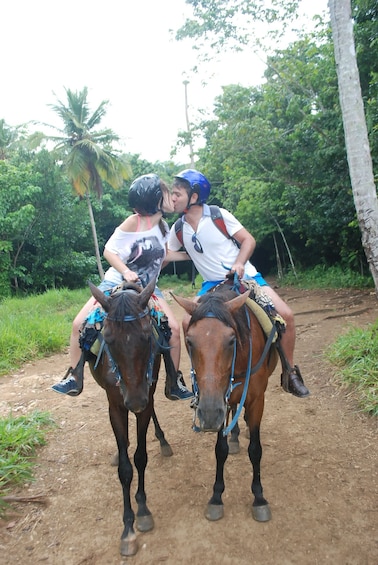 A couple on horses kiss during a trail ride