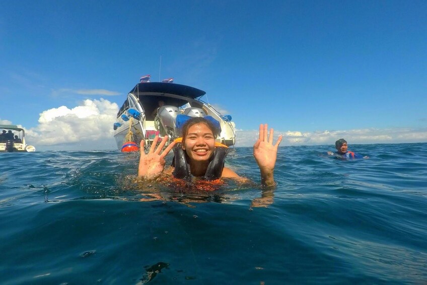 Woman snorkeling near a speed boat in Koh Kradan
