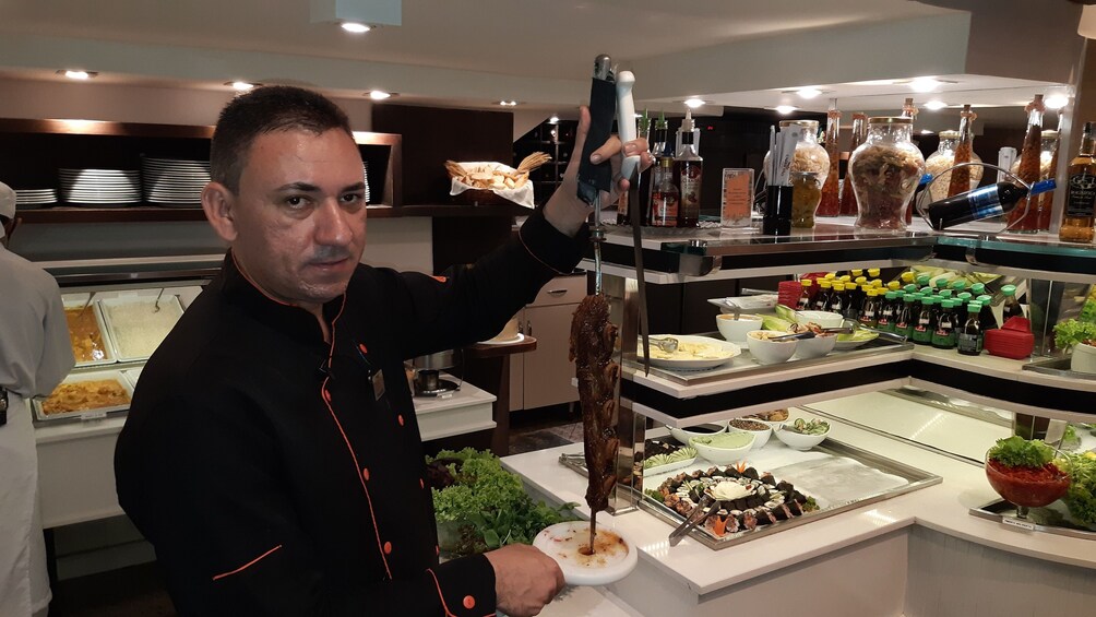Chef holds up string of ribs at steakhouse in Rio de Janeiro, Brazil