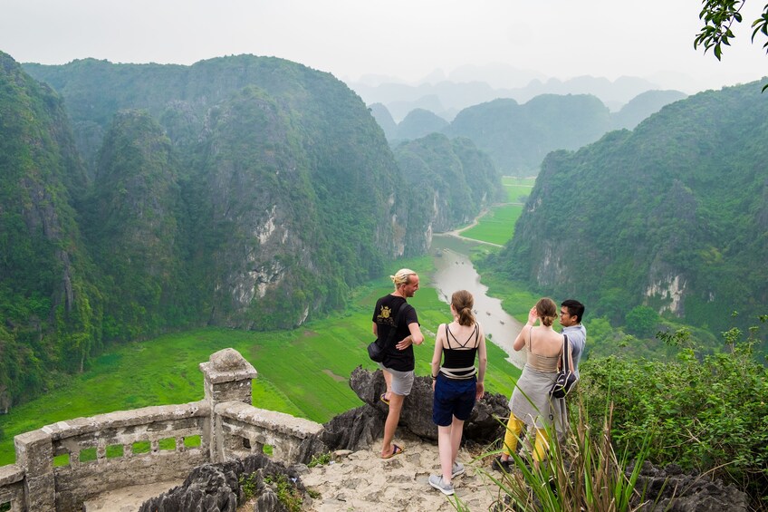 Tourists stand at overlook at Mua Caves on a foggy day