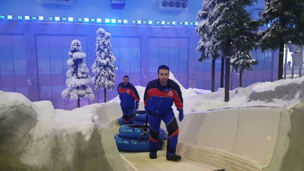 Men pull inner tubes up fake snowy hill in the Mall of Egypt