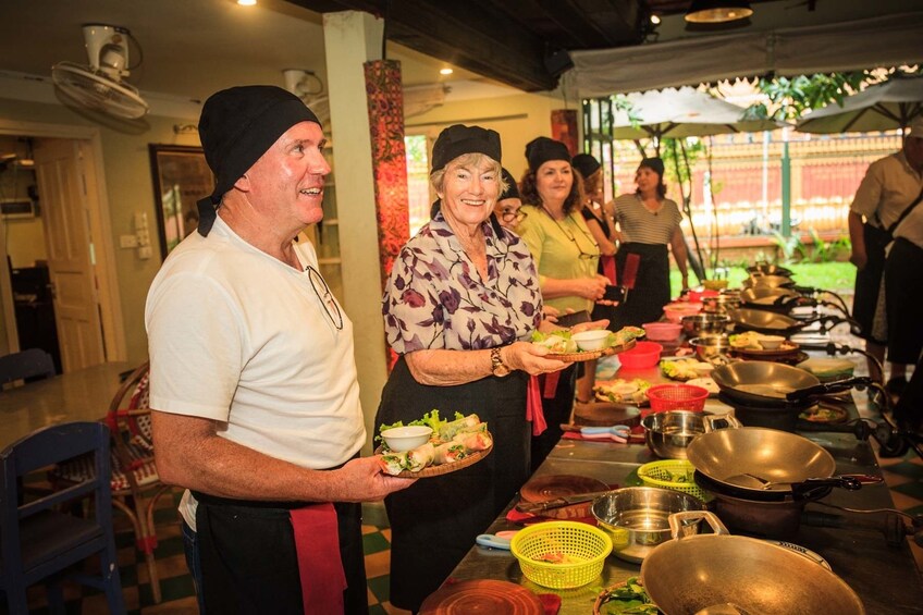 Pariticants of cooking class hold up finished dishes