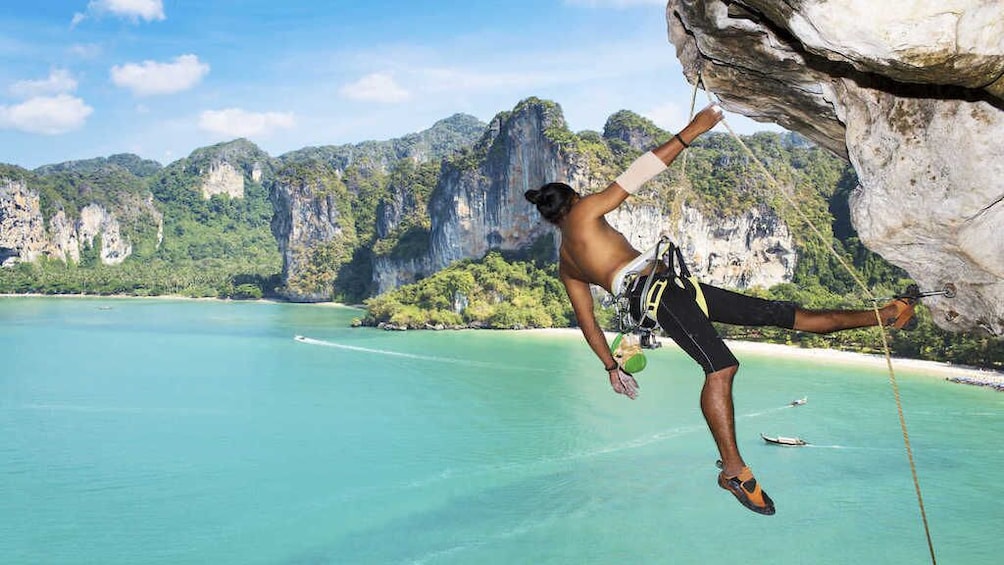Man hangs off of rocks in Krabi, Thailand