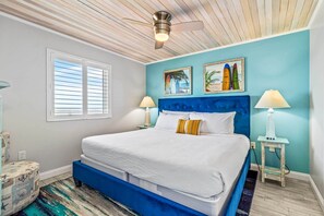 Unwind in this cozy bedroom featuring a plush king-sized bed, nautical-inspired decor, and a ceiling fan for added comfort. Wake up refreshed with natural light and glimpses of the ocean just outside your window—your perfect seaside retreat!