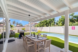 A beautiful backyard area featuring a dining table, BBQ grill, hammock, and a refreshing pool, creating a perfect oasis for leisure.