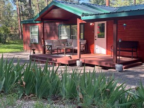 Covered deck surrounded by tall pines — enjoy your morning coffee or evening glass of wine.