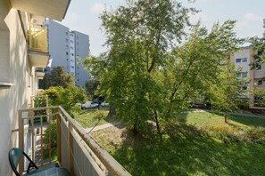 A balcony view overlooking a green courtyard with mature trees and surrounding buildings, perfect for enjoying fresh air.
