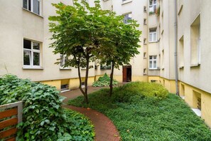 A view of the green courtyard with a small path and lush plants, creating a peaceful outdoor area.
