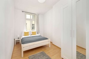 A cozy bedroom featuring a single bed, a large wardrobe, and minimalist decor for a simple and inviting look.
