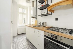 A compact kitchen with white cabinets, a wooden countertop, and modern appliances, creating a functional cooking space.
