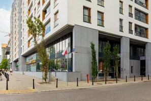 A modern apartment building with large windows and a stylish facade, located in an urban area.