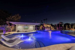 Enjoy the hot tub and resort-style pool, illuminated at night.