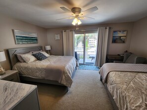 spacious bedroom with a balcony and two queen beds with blackout curtains