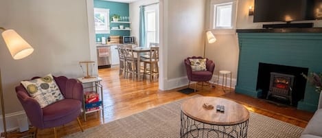 Cozy up by the fireplace in this living room, where a circular table adds a touch of elegance and encourages intimate conversations.