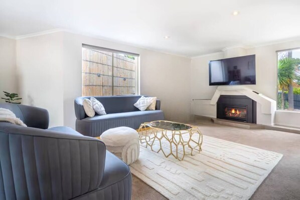 Unwind in the living room, where plush seating, a sleek coffee table, a wall-mounted TV, and a cosy fireplace create the perfect space to relax and recharge.