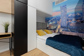 A comfortable bedroom with a double bed, blue bedding, and a cityscape wall print, adding a vibrant touch to the design.