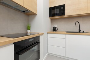 A sleek kitchen with white cabinets, wooden countertops, and black appliances, blending functionality and modern aesthetics.