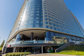An exterior view of a modern high-rise building with a unique curved design and a polished facade.
