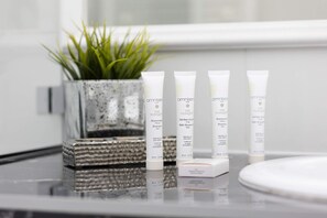 A close-up of complimentary toiletries and a decorative plant on a bathroom counter, emphasizing attention to detail.
