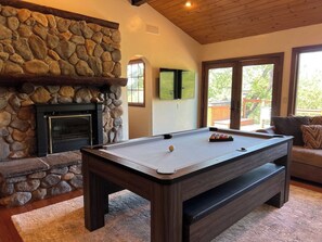 A second living room with a pool table, additional ping table topper, speaker system, and 55" 4K TV.