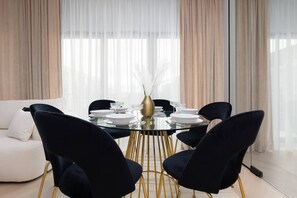 A dining area with a round table, black chairs, and large windows, blending elegance and functionality.

