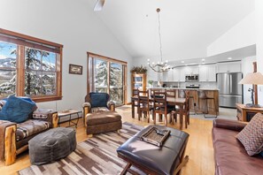 Spacious living area with mounted flat screen TV, gas fireplace, hardwood floors, vaulted ceiling and access to the private balcony.