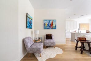 LIVING ROOM: Discover a cozy corner in our property, featuring two single-seater couches framing a small table with an elegant lampshade. A soft white faux fur mat adds a touch of luxury underfoot, while a beautifully designed wooden furniture piece completes the inviting setting.