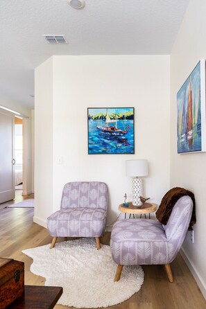 LIVING ROOM: Dive into comfort with our intimate corner featuring two lavender single-seater couches, delicately framed by a mini table adorned with a chic Nordic lampshade. The soft faux fur mat underfoot adds a touch of luxury to this cozy retreat, inviting you to unwind and savor the moment.