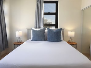 Bedroom with view of ocean from behind bed.