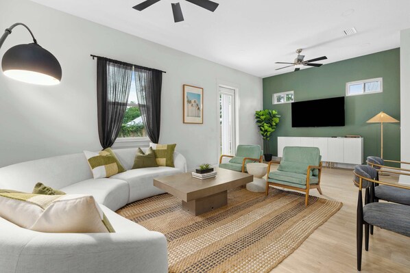 Open-concept living room with plush seating, large windows, and a cozy atmosphere—perfect for family relaxation or movie nights. - The Sandbar - Panama City Beach, FL