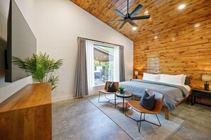 Bedroom #1—king bed, 65" Smart TV, fan, dresser, seating area, nightstands.