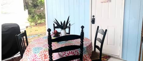 Bbq grill close to dining table beneath sheltered porch.