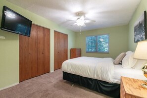 This upstairs bedroom is the perfect escape, featuring a queen-sized bed, ample closet space, and a wall-mounted TV.