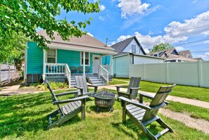 The backyard includes a cozy fire pit surrounded by Adirondack chairs, creating a welcoming outdoor space