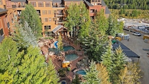 An aerial view of the wonderful shared outdoor pool guests have access to. The pool area includes two hot tubs, a wading pool, and a heated pool with a slide.