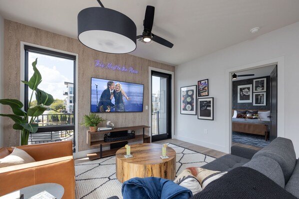 Bright open concept living area with floor to ceiling windows providing panoramic views of Midtown! Features designer furniture, smart TV, and access to private balcony.